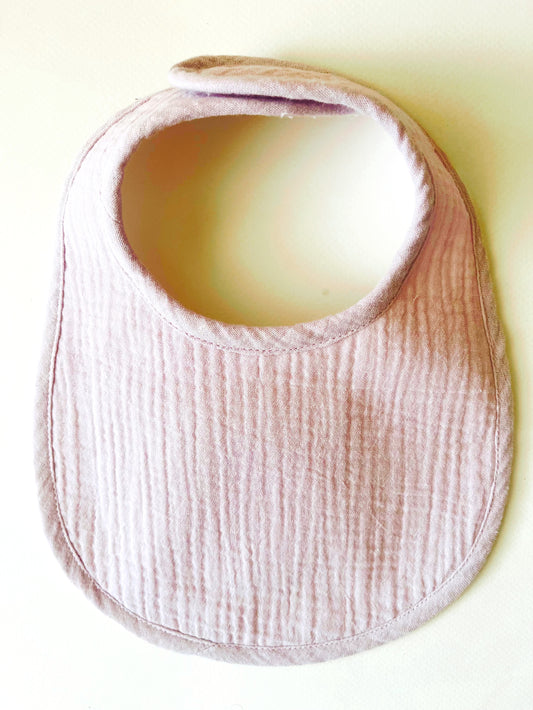 Babero de muselina color malva liso con cierre en velcro adaptable al crecimiento del bebé