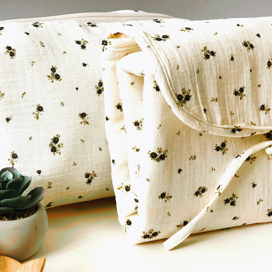 Conjunto de cambiador de paseo plegado y neceser de la misma colección, muselina de color beis con delicadas flores grises y verdes