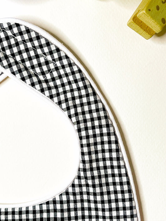 detalle del acabado del babero en cordón de color blanco y cierre en velcro adaptable al crecimiento del bebé.