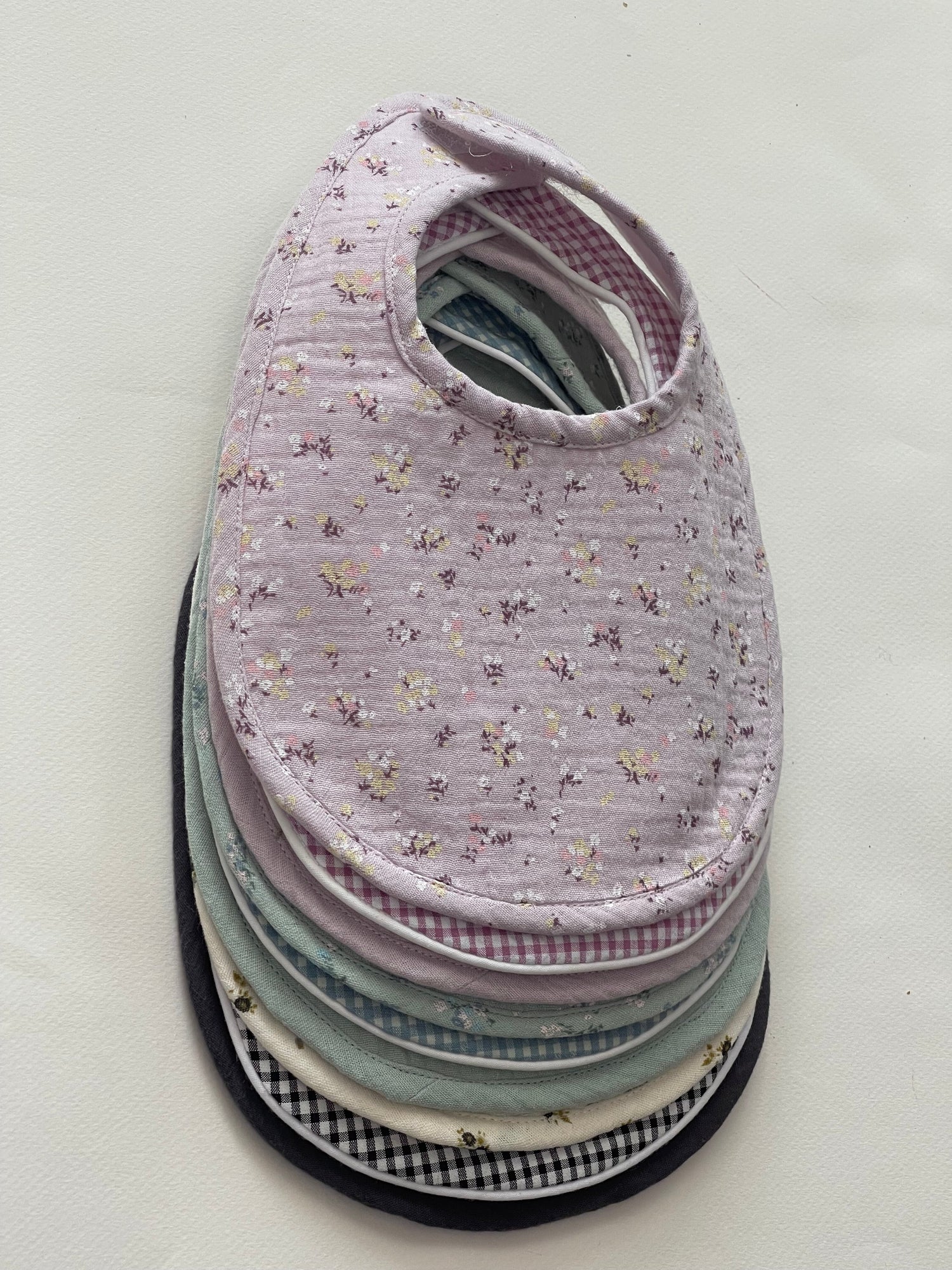 babero en algodón de muselina en el exterior y guata impermeable en el interior, cierre con velcro