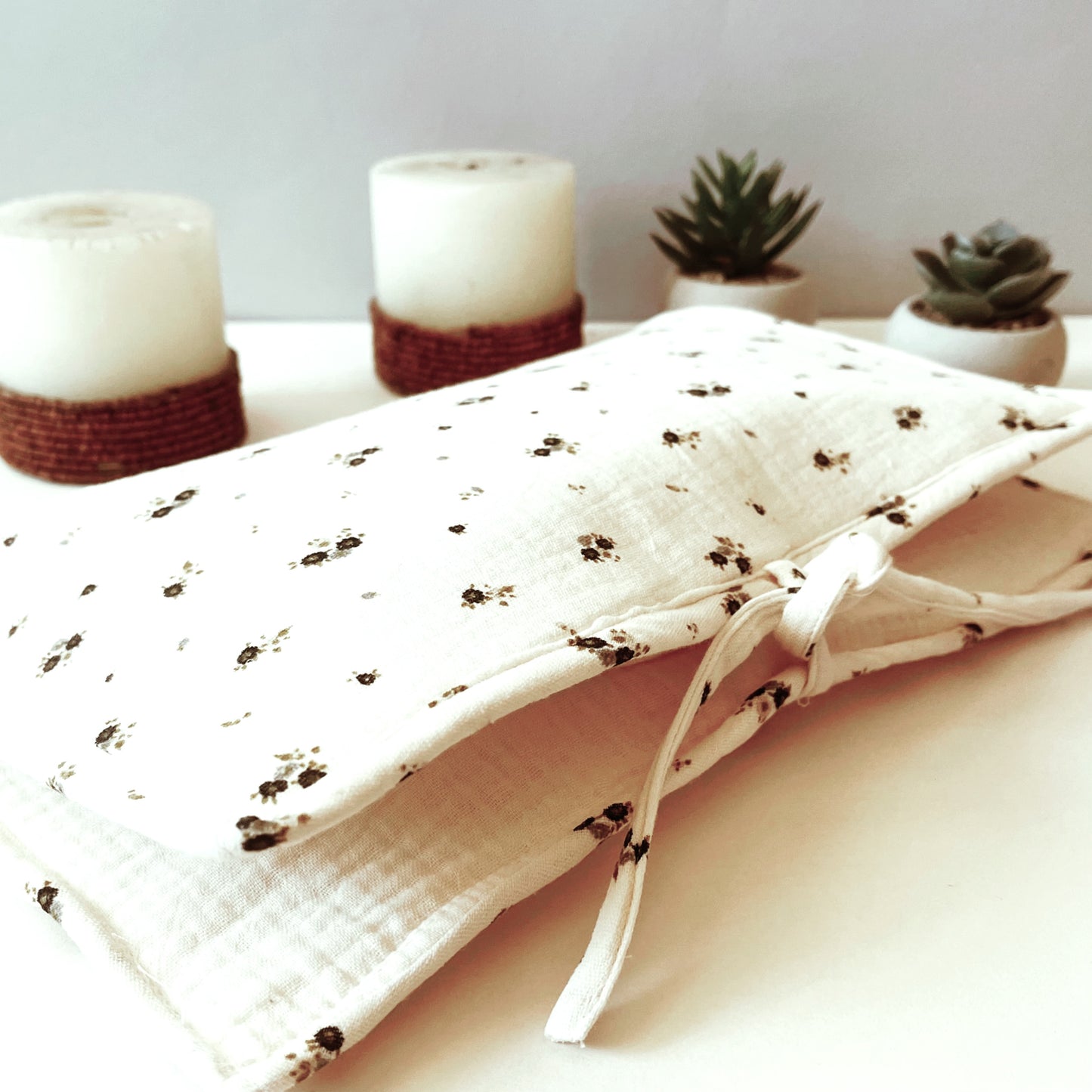 Porta toallitas cerrado en muselina beis con flores grises y verdes; cierre con lazo. decoración de velas y plantitas