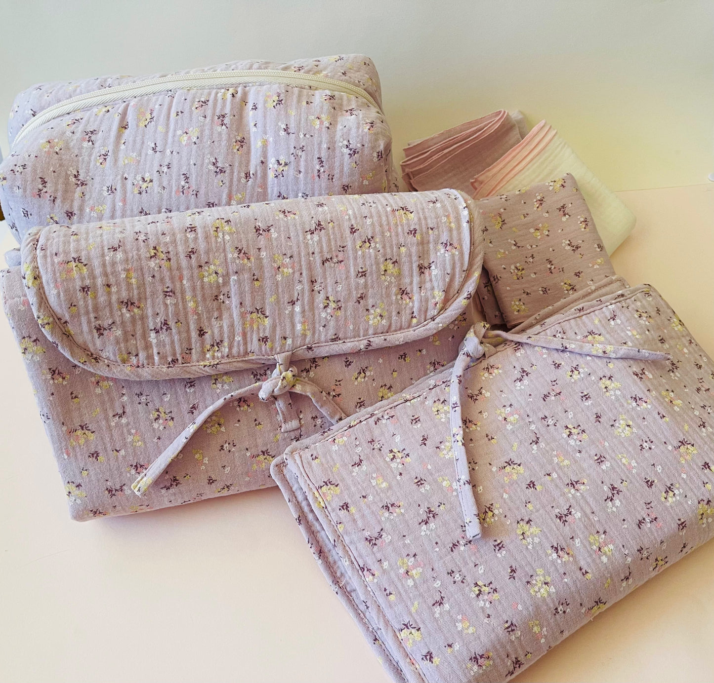 Conjunto de neceser, cambiador de paseo,  y muselinas en tejido de muselina malva con flores amarillas y blancas