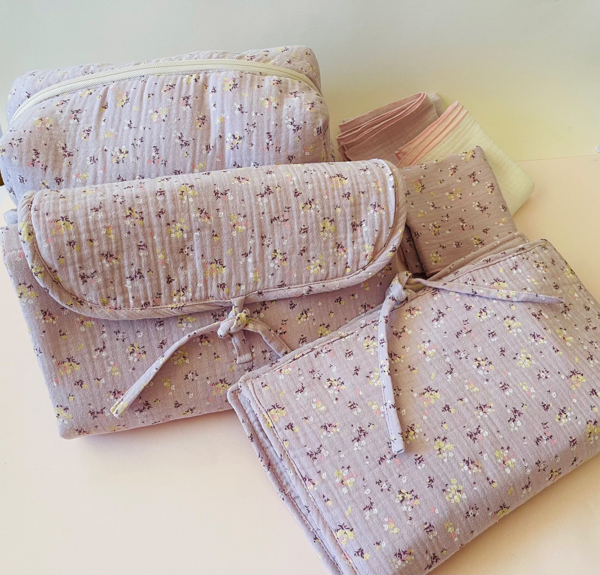 Conjunto de neceser, cambiador de paseo,  y muselinas en tejido de muselina malva con flores amarillas y blancas