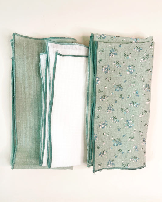 Conjunto de tres muselinas en color verde liso en la izquierda, en el centro blanco liso y a la derecha verde con florecitas azules y blancas. terminación en hilo verde