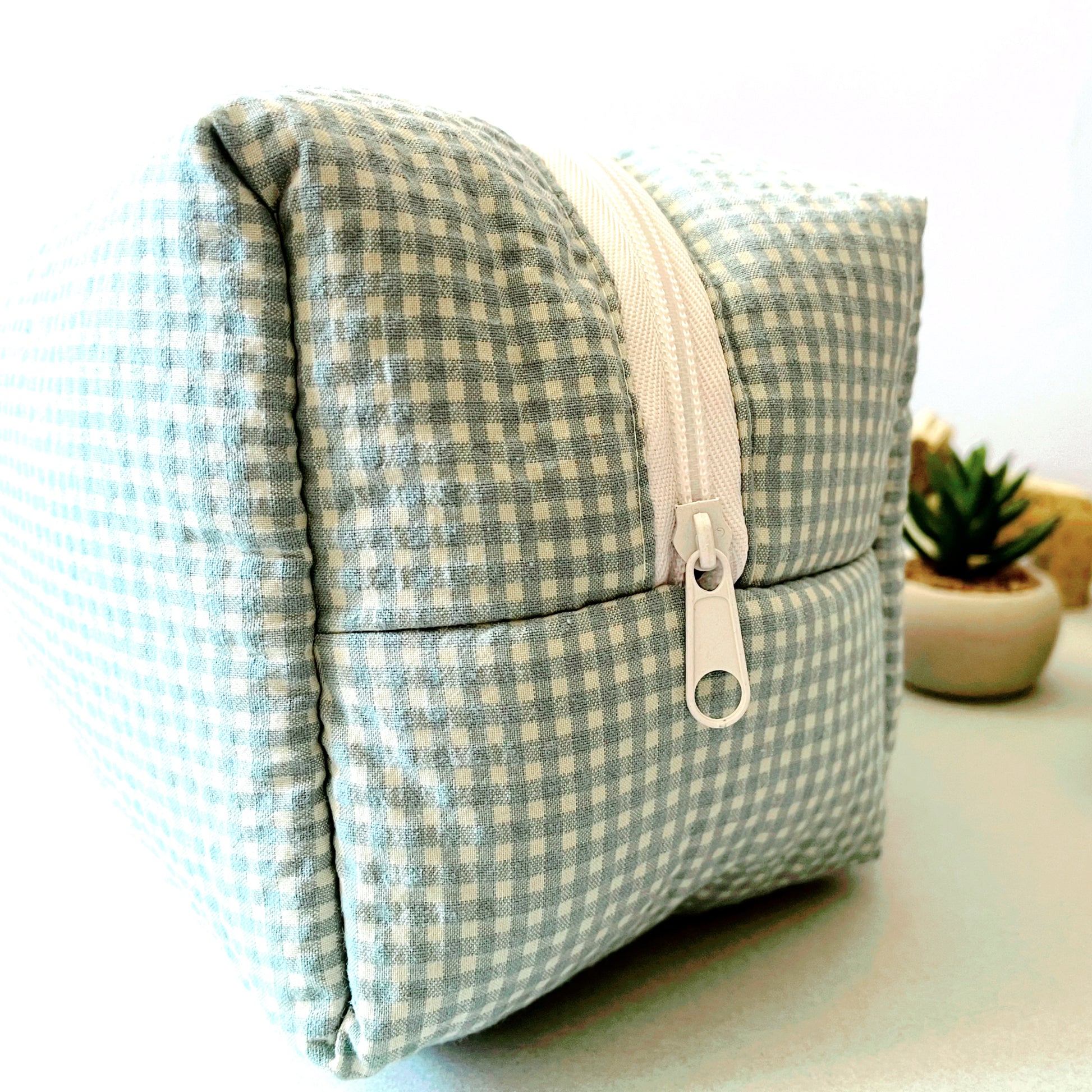 Vista lateral del neceser de estampado cuadros verde menta y blanco, cierre con amplia cremallera