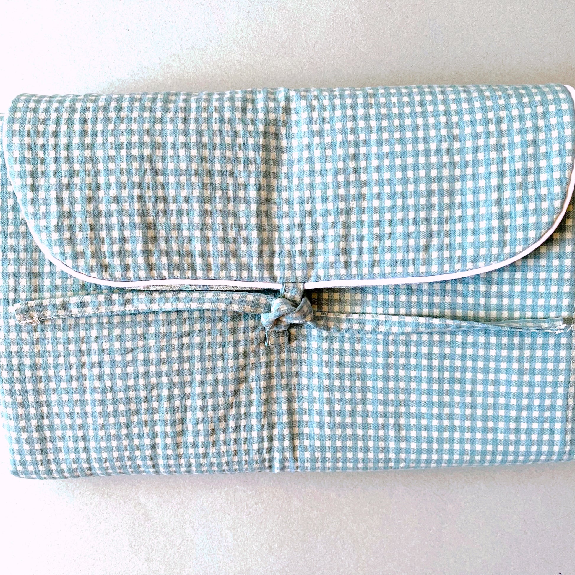 Parte frontal del cambiador de paseo donde se aprecia el perfecto acabado de la solapa en un cordón de vibo blanco y cierre en lazo