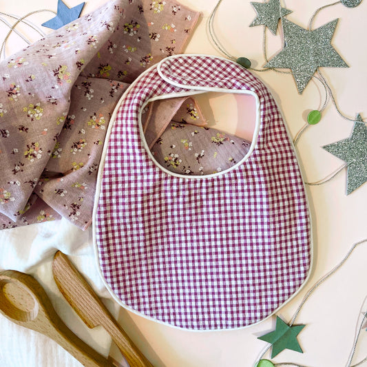 Babero  de tejido estampado cuadros rosa y blanco; muselina de color malva con flores amarillas y burdeos