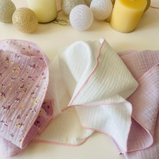 Conjunto de tres muselinas: muselina de color malva con florecitas amarillas y burdeos a la izquierda, en el centro muselina de color blanco y muselina de color malva liso a la izquierda