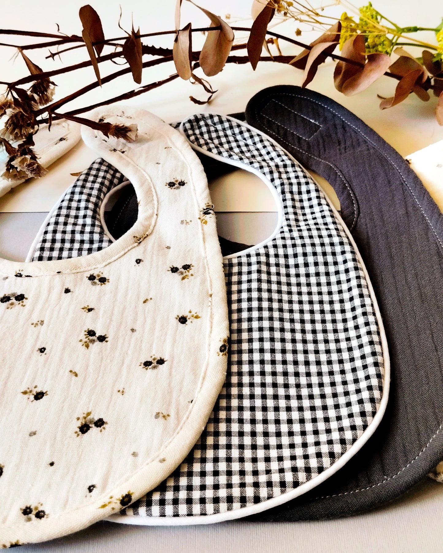 Babero de muselina 100% algodón  de color beis con flores grises y verdes- Colección PALITO