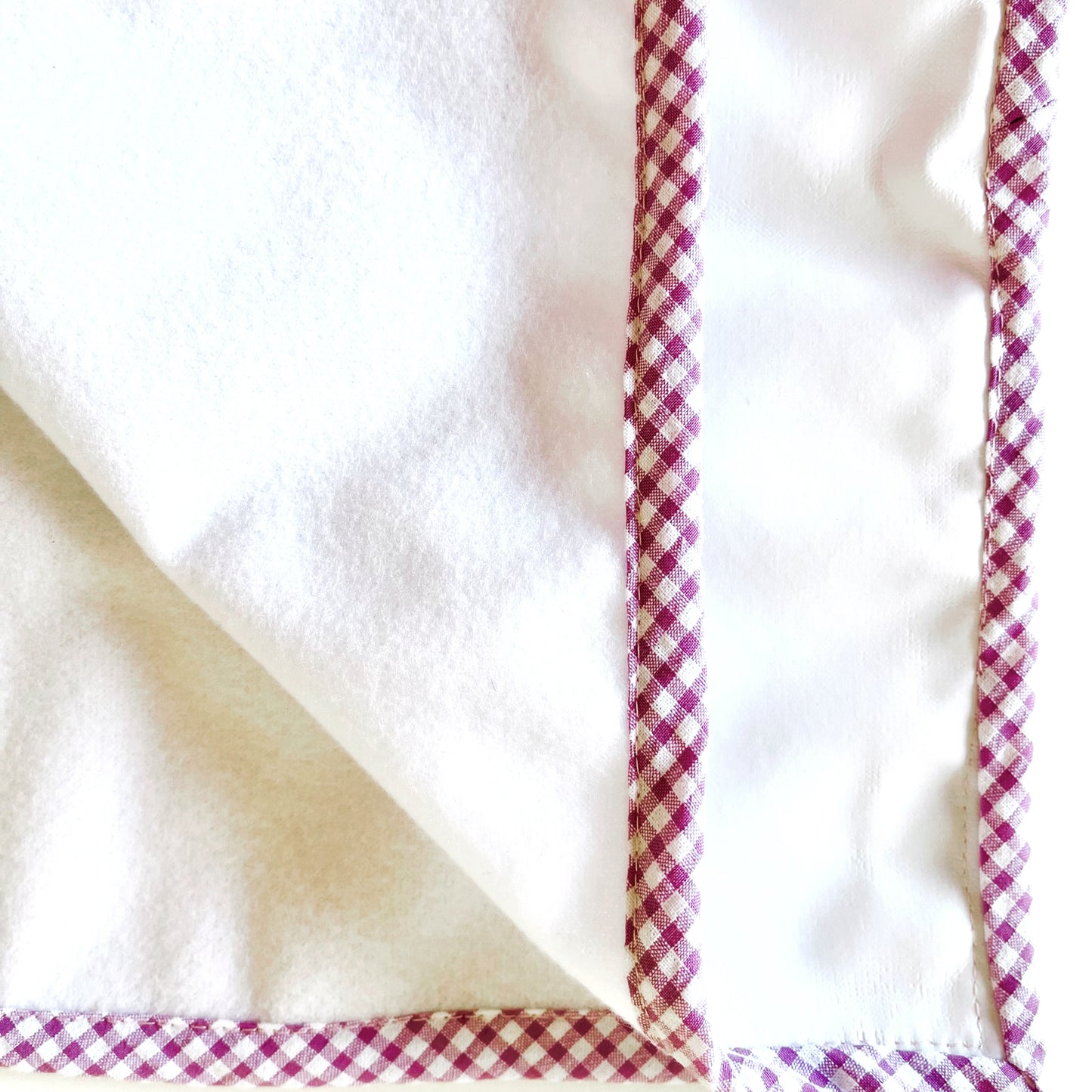 Alfombra de cambiador de paseo donde se aprecia el tejido de la parte delantera, de suave guata, y el de la parte trasera que es impermeable.