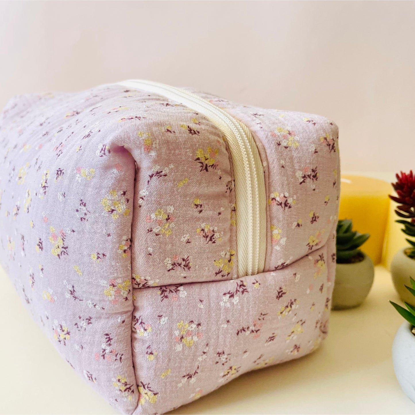 Vista lateral del neceser en muselina  color malva con flores y cierre con cremallera