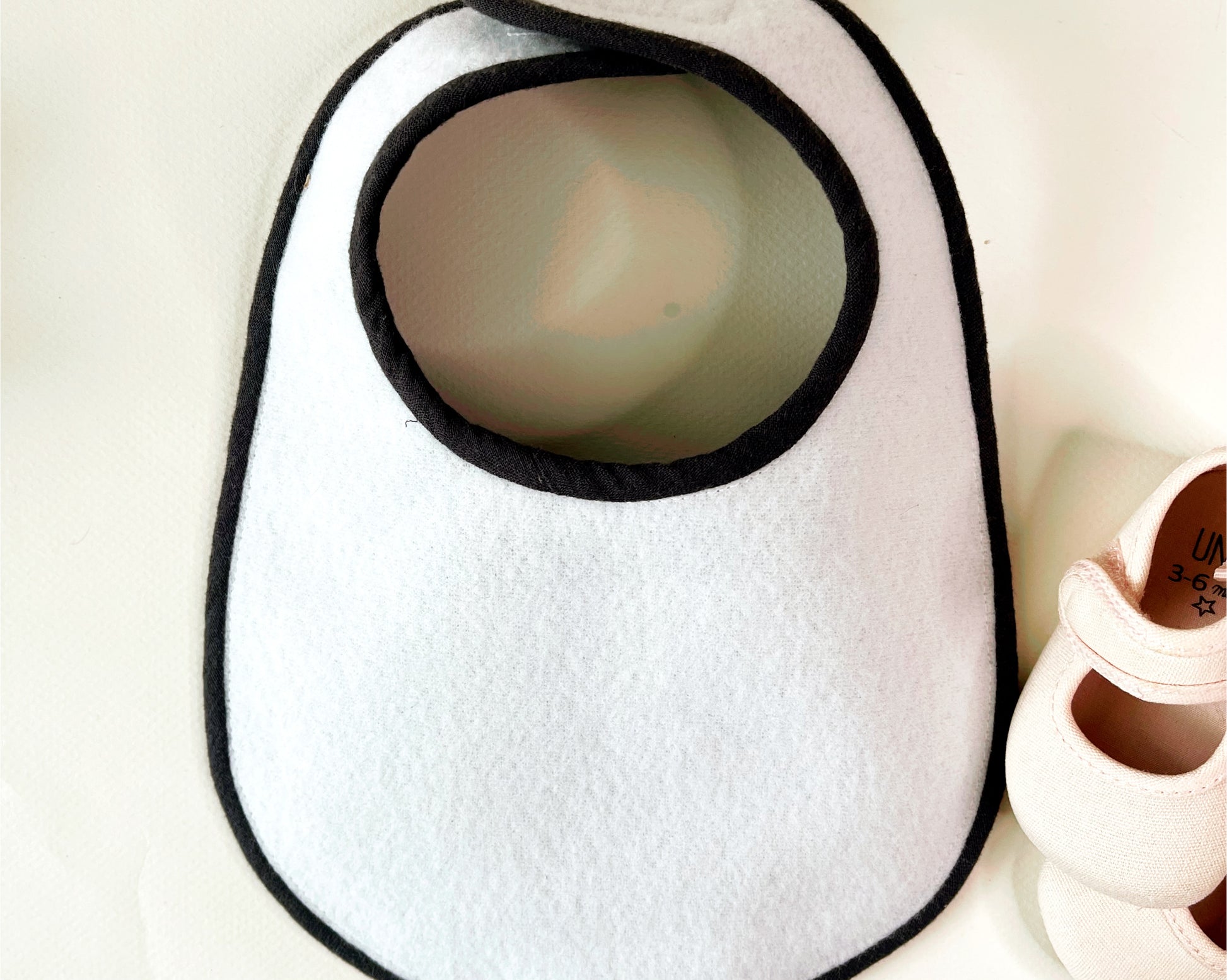 parte trasera del babero de delicada y dulce guata impermeable al tacto y acabado en el mismo color de la tela