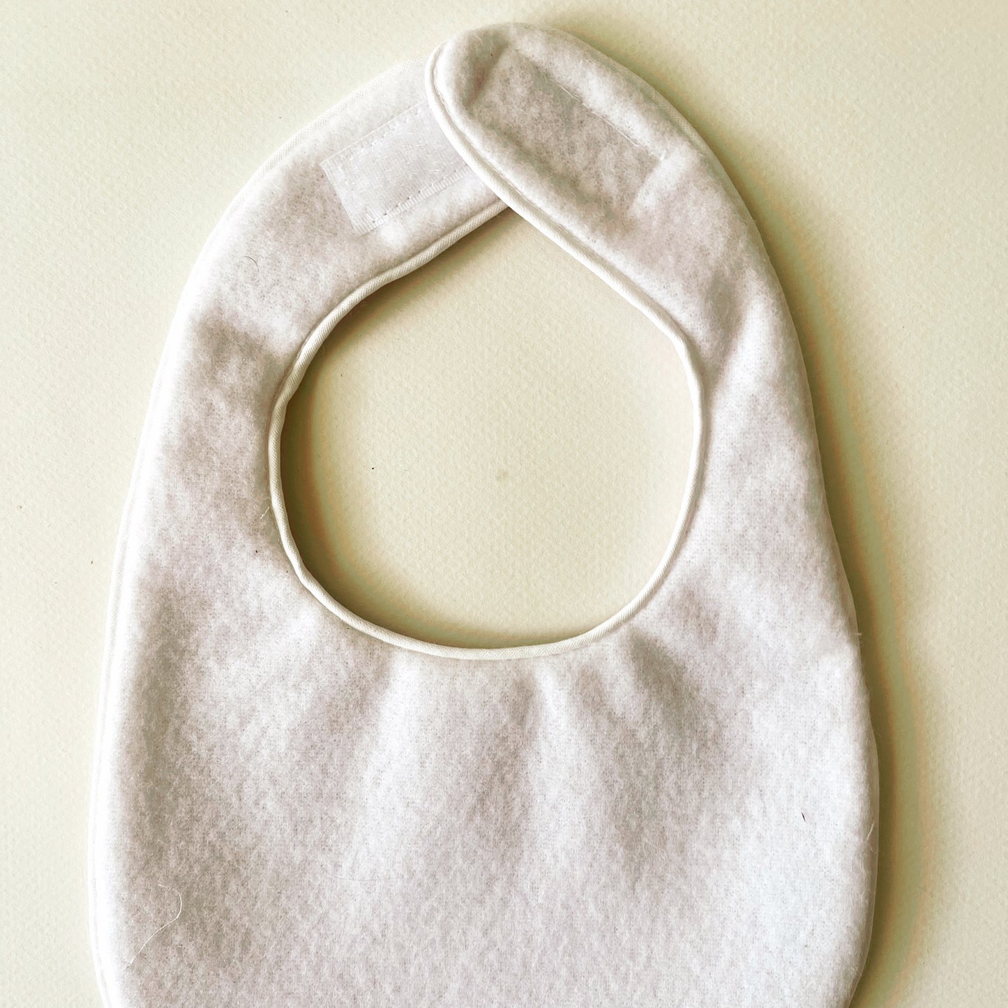 Parte interior del babero en suave y delicada guata impermeable; cierre con velcro adaptable al crecimiento del bebé.