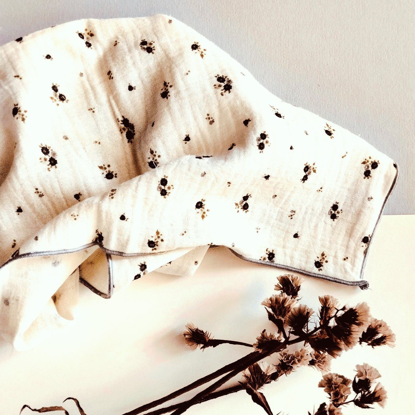 Muselina beis con flores gris y verde, acabado en hilo gris