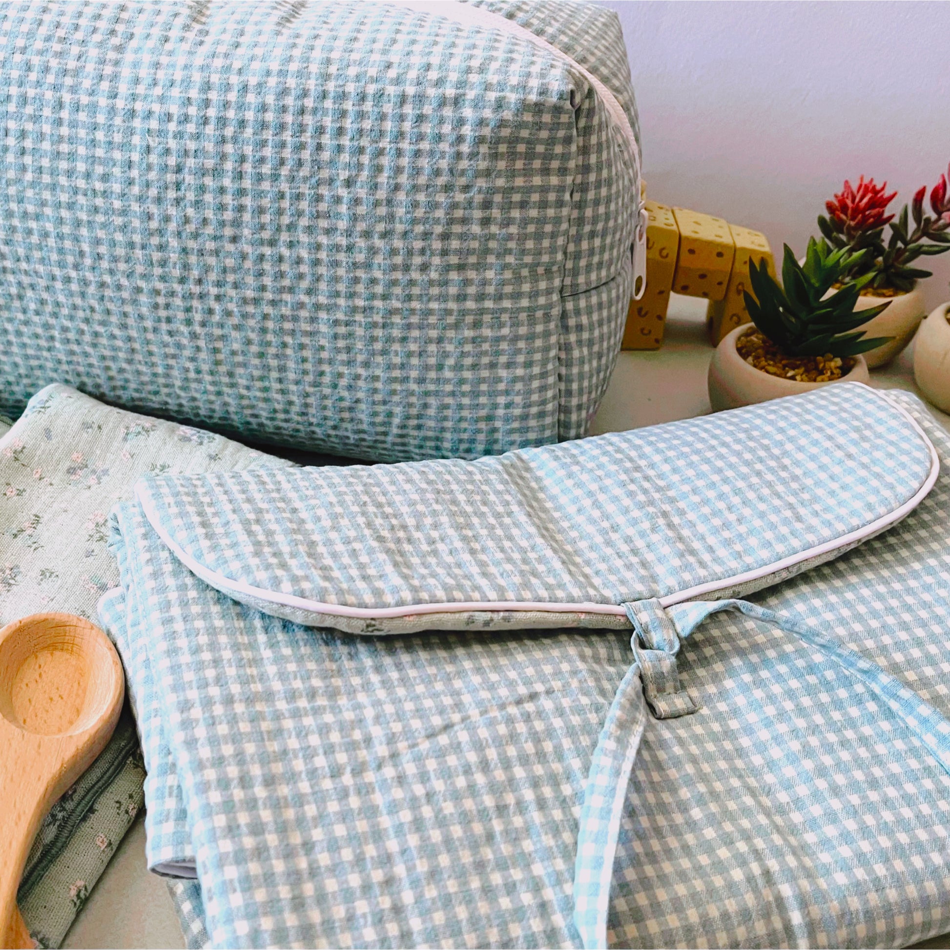 Conjunto de cambiador de paseo, neceser en la parte de atrás y muselina de color verde con flores azules