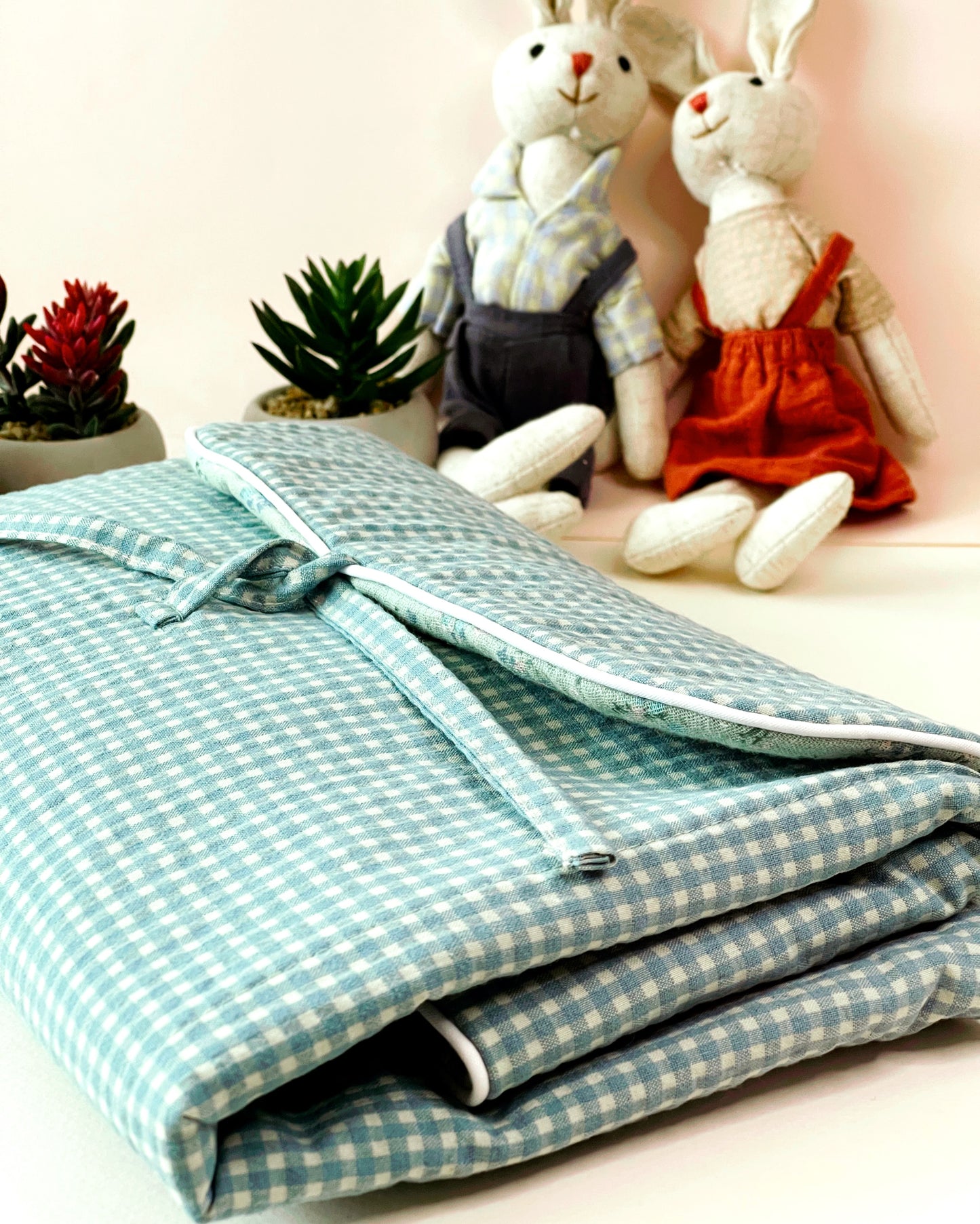 Vista del cambiador plegado donde se aprecia la forma de plegarlo en dos veces Cierre en lazo. Decoración de peluches y plantitas.