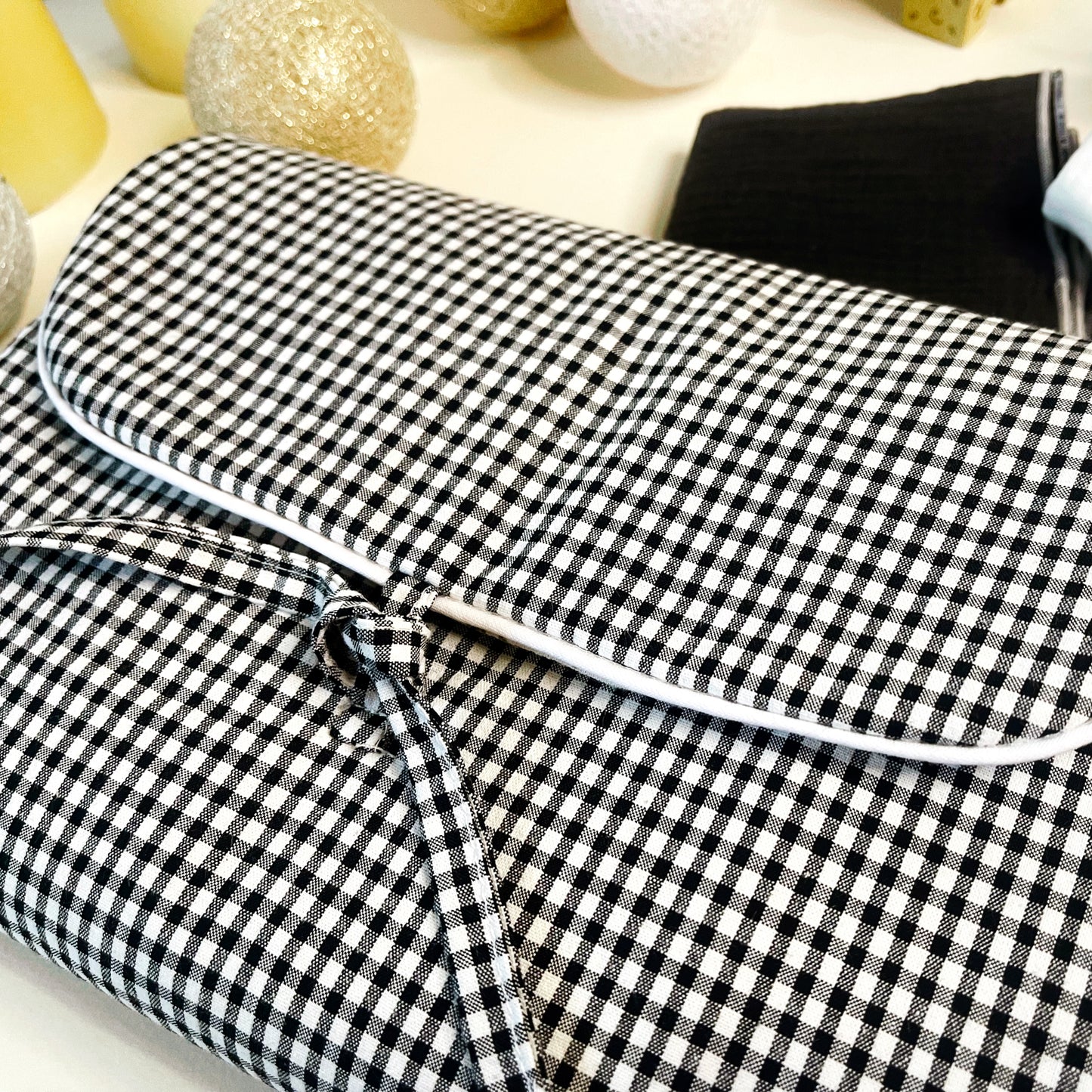 Vista del cambiador de paseo cerrado, estampado de cuadros negros y blancos y terminación en cordón blanco y cierre en lazo