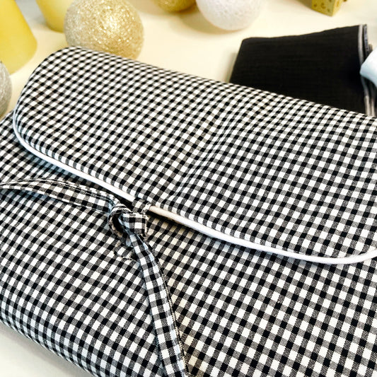 Vista del cambiador de paseo cerrado, estampado de cuadros negros y blancos y terminación en cordón blanco y cierre en lazo