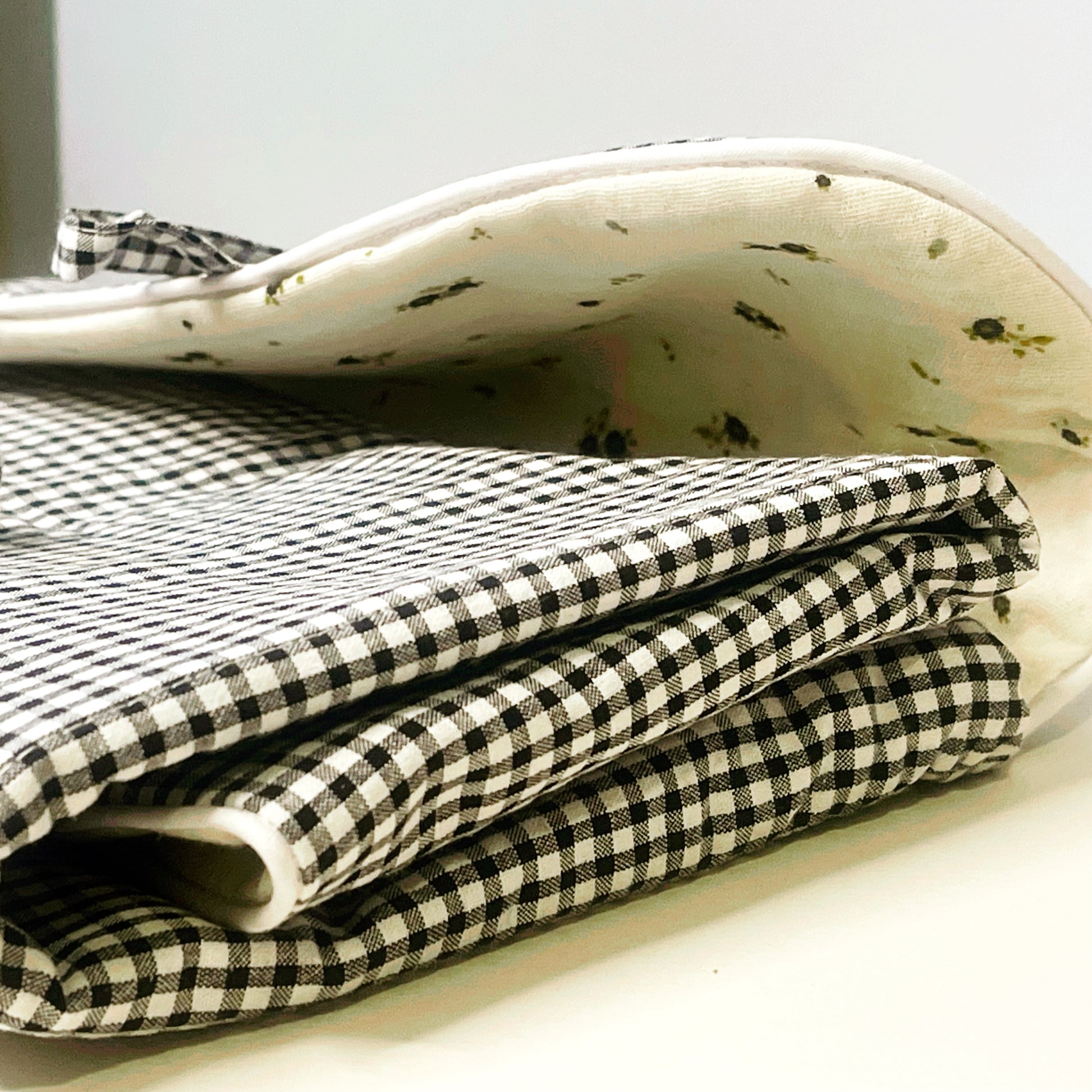 Cambiador de paseo cerrado ; combina el estampado de cuadros negros y blancos en el exterior y en el interior la muselina de color  beis con flores grises y verdes