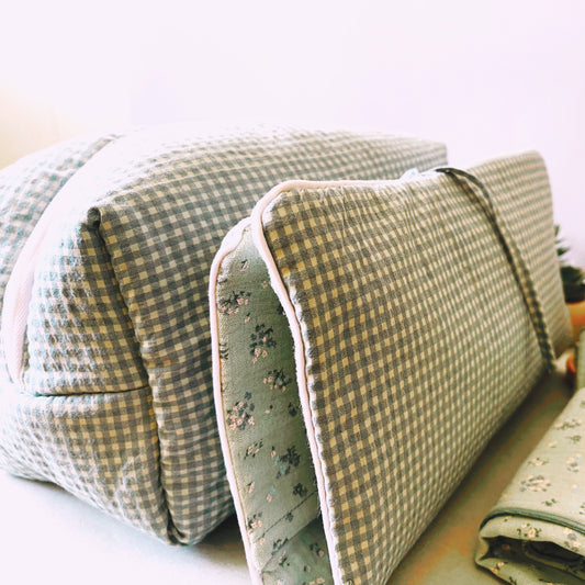 Conjunto de neceser y portatoallitas en estampado de cuadros verde y blanco; cierre con cremallera y lazo respectivamente; muselina de color verde con florecitas azules.