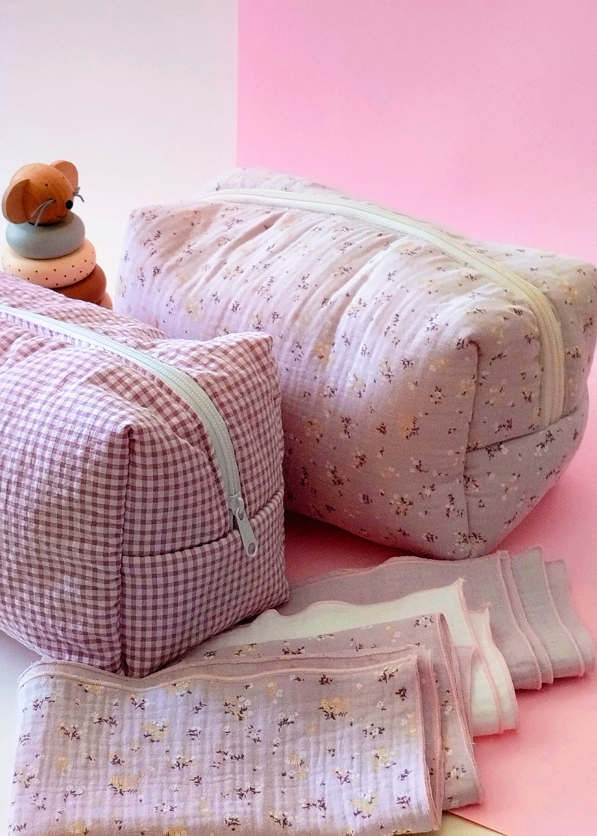 Conjunto de neceser en muselina malva con pequeñas flores amarillas y burdeos y en estampado de cuadros rosa y blanco; ambos con cierre de cremallera; muselinas de color malva con florecitas amarillas y blancas, de color blanco liso y de color malva liso