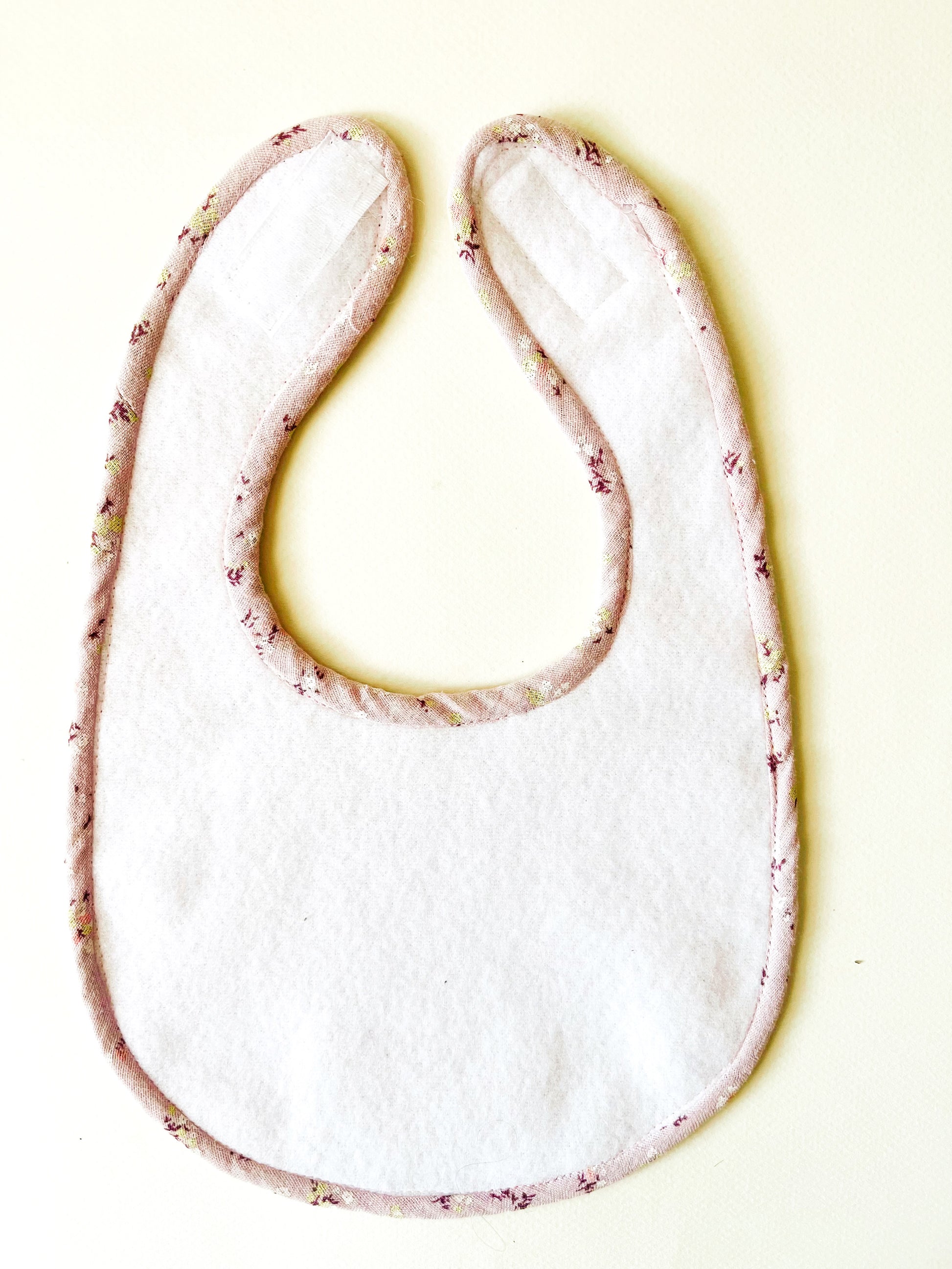 parte trasera del babero donde se aprecia la suave y delicada guata impermeable y el vibo confeccionado en la misma tela