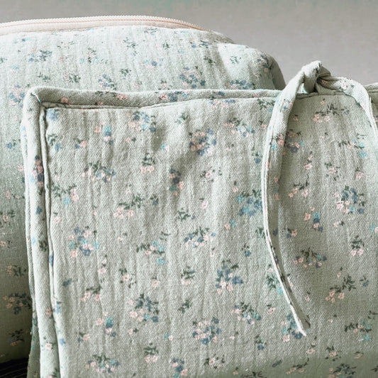 Conjunto de porta toallitas en muselina de color verde menta y flores azules y blancas con cierre en lazo; neceser del mismo tejido y cierre con cremallera