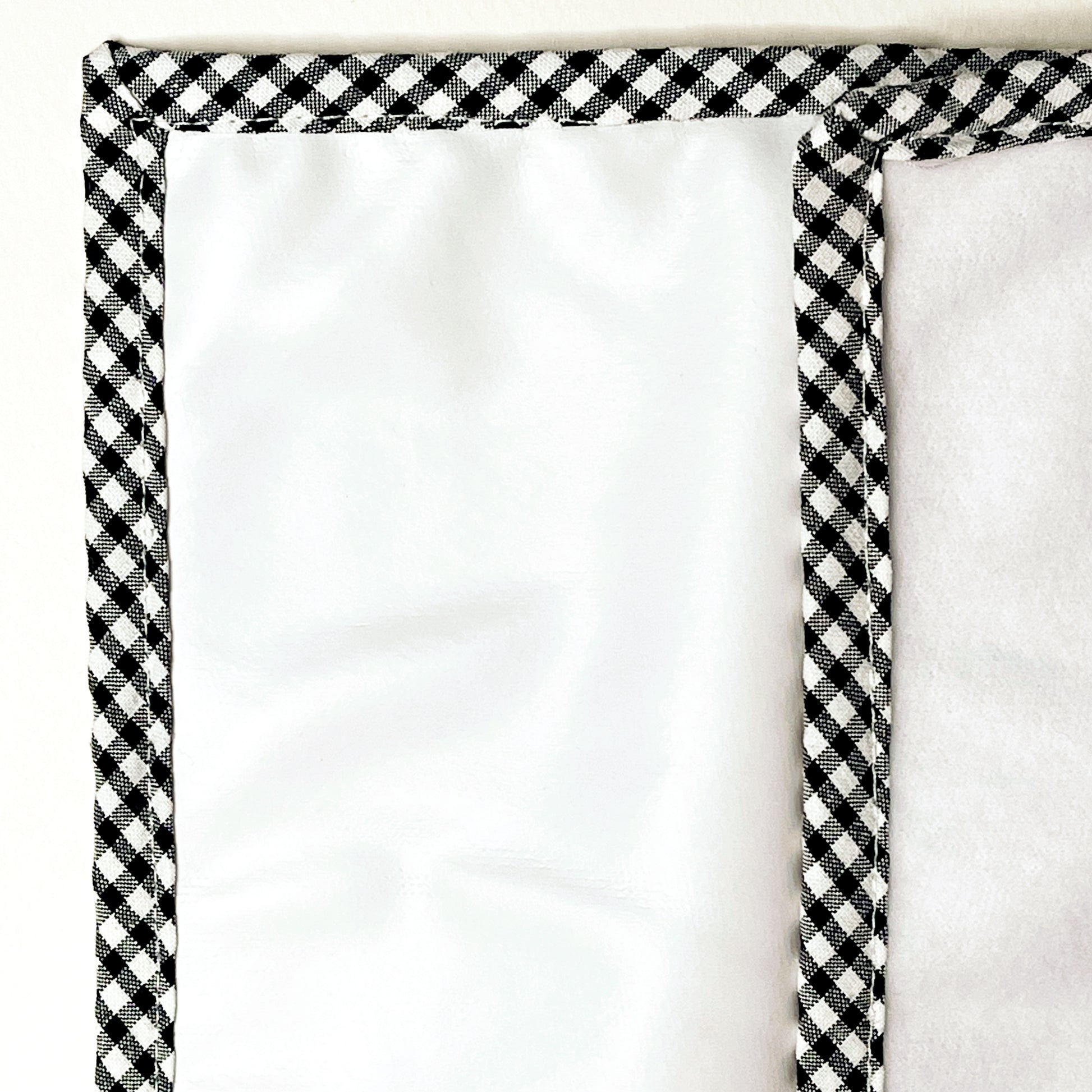 Alfombra del cambiador de paseo para poner el bebé de suave guata en la parte delantera e impermeable en la parte trasera; acabado en estampado de cuadros de color negro y blanco.