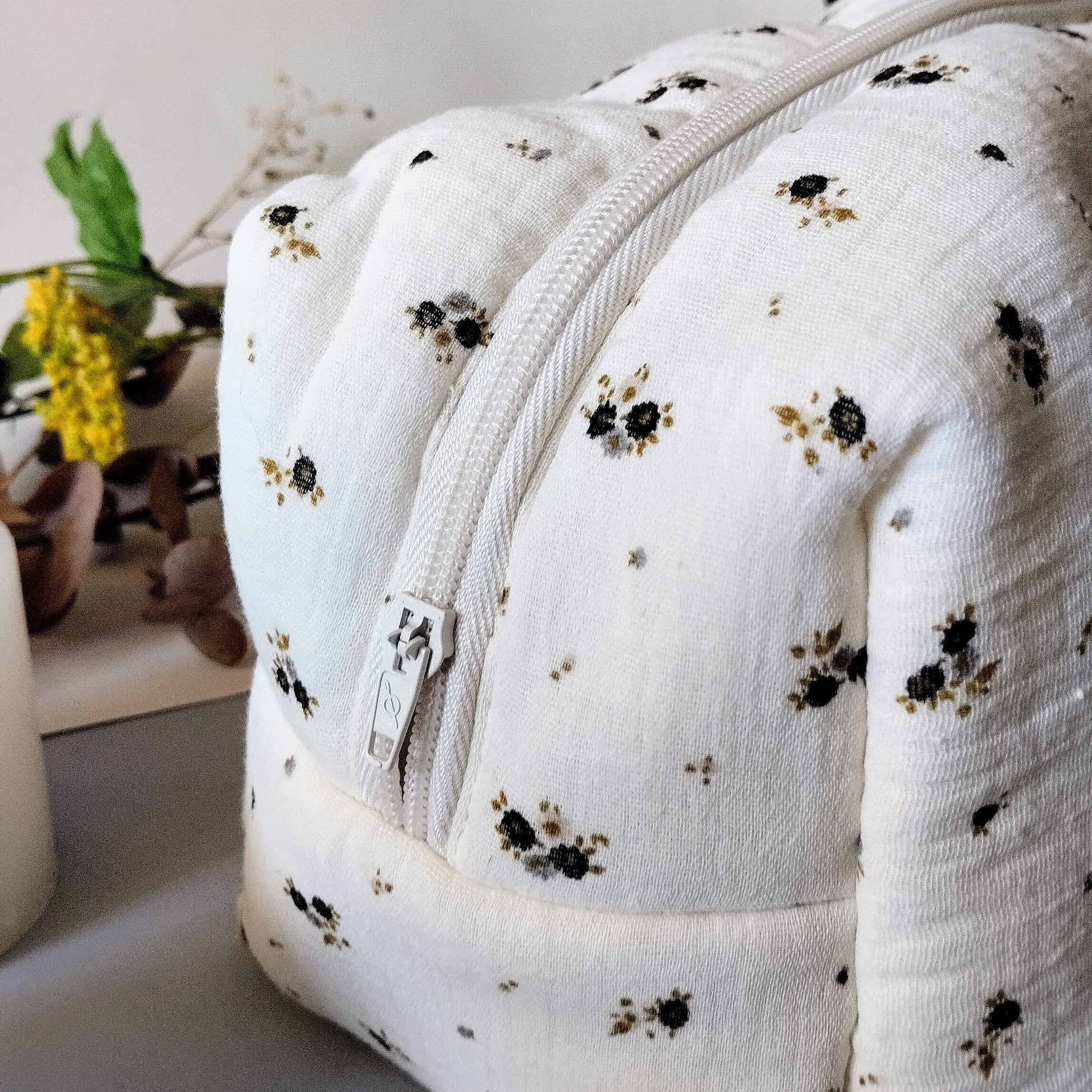 lateral del neceser de muselina beis con flores grises y verdes; cierre con cremallera